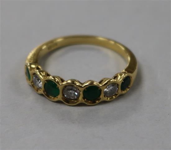 An 18ct gold, emerald and diamond set seven stone half hoop ring, size O.
